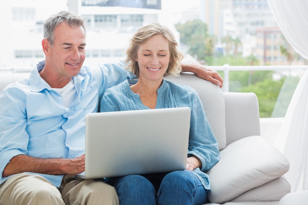 Cheerful couple relaxing on their couch using the laptop at home